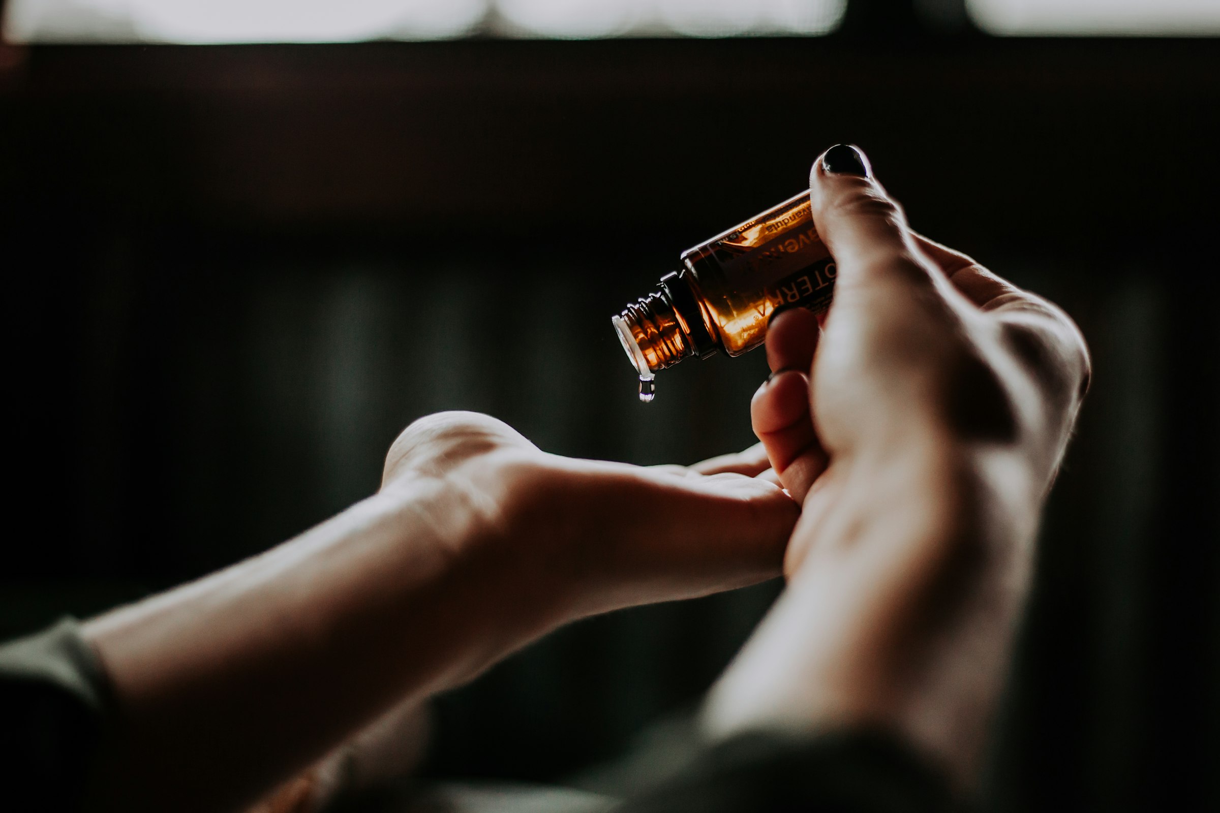 Warm medicated oil being poured in a slow stream during a Shirodhara treatment